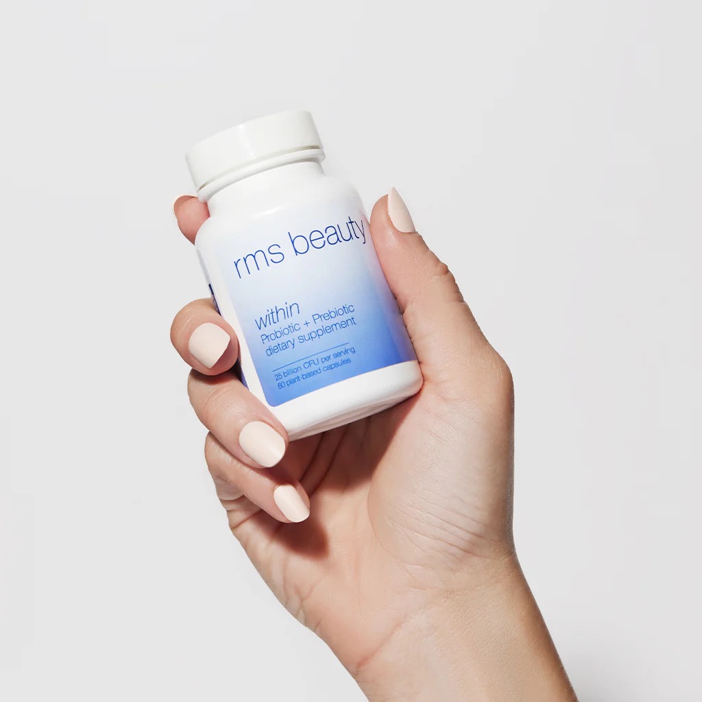 A hand holding a bottle of RMS beauty's probiotics. 