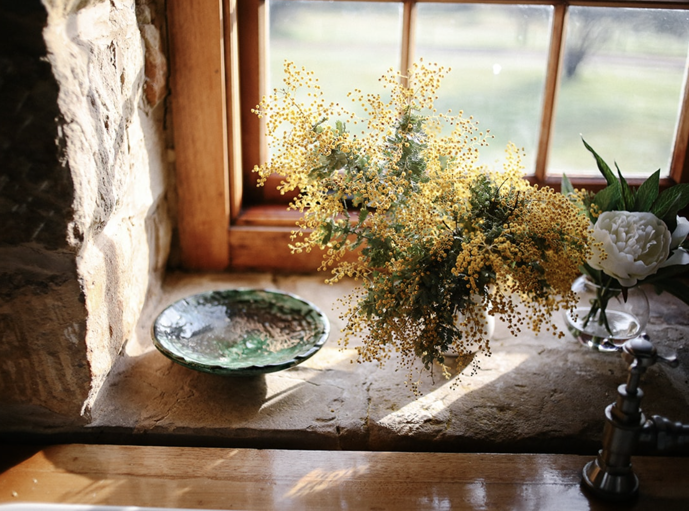 A ceramic dish and a plant sit on a windowsill. 