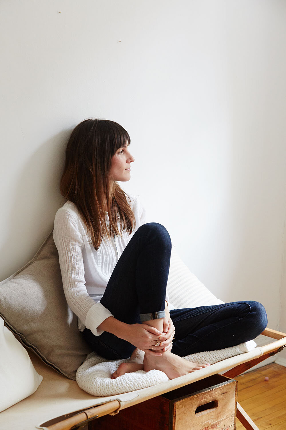 An adult women sits on cushions and looks on. 