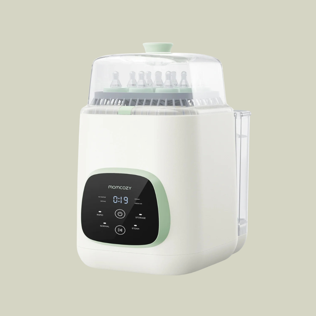 White and mint green electric baby bottle sterilizer with digital display, containing several baby bottles and nipples under a transparent lid, set against a plain light-colored background.