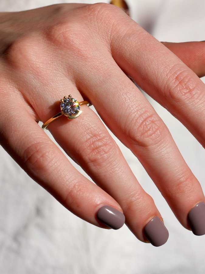 1.5 carat solitaire diamond ring glimmering in the sun on a models hand