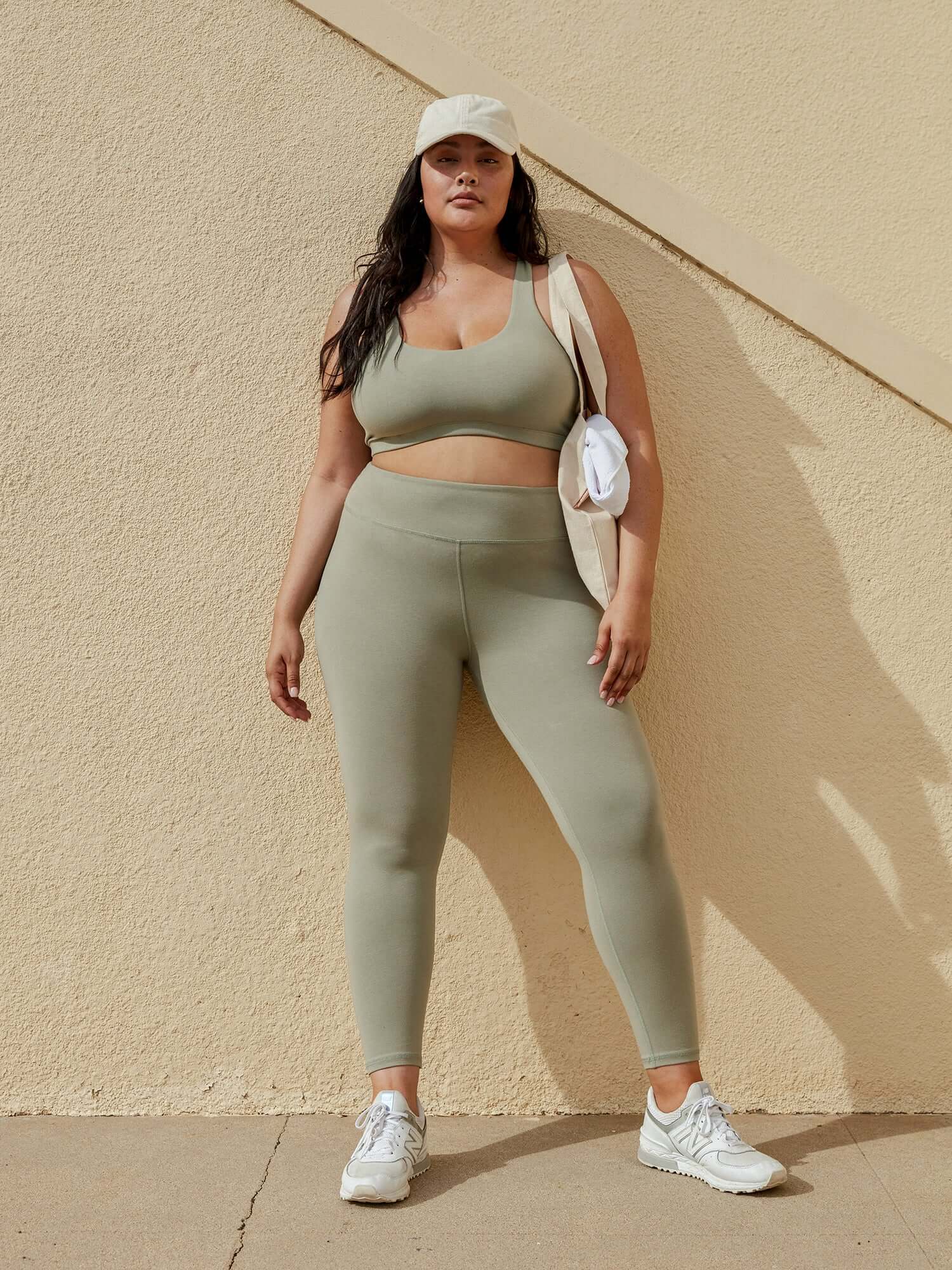 A model wears a sage green cotton legging and bra set. 