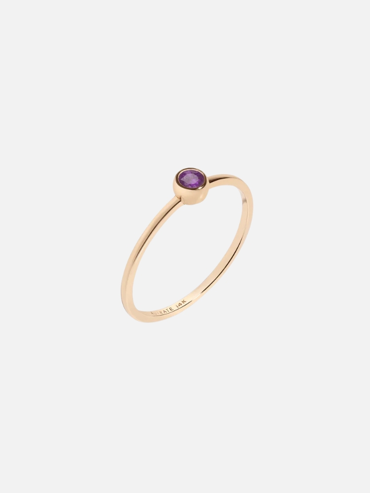 Gold ring with a single purple gemstone.