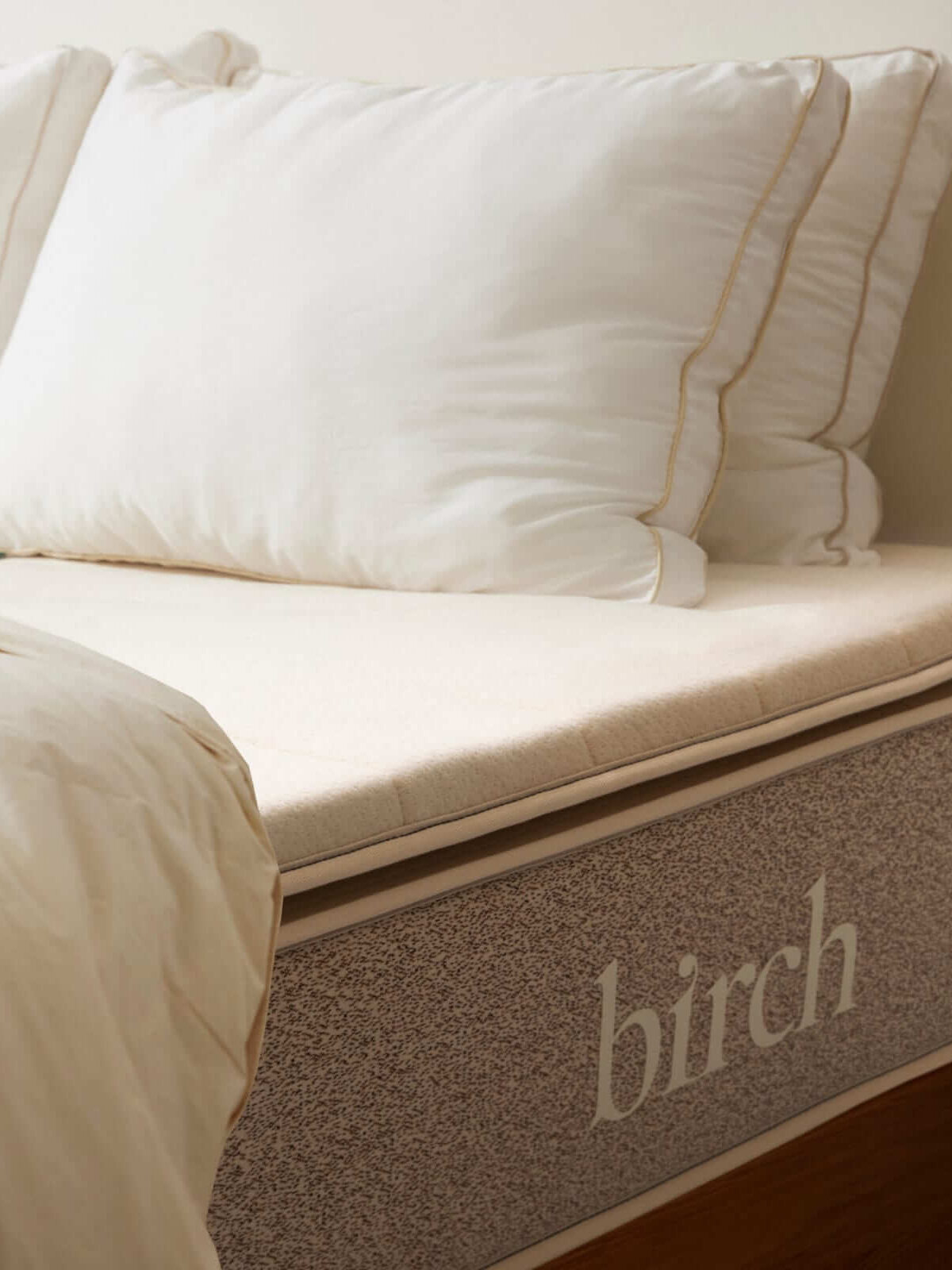 The Birch organic mattress topper and pillows on an unmade bed.