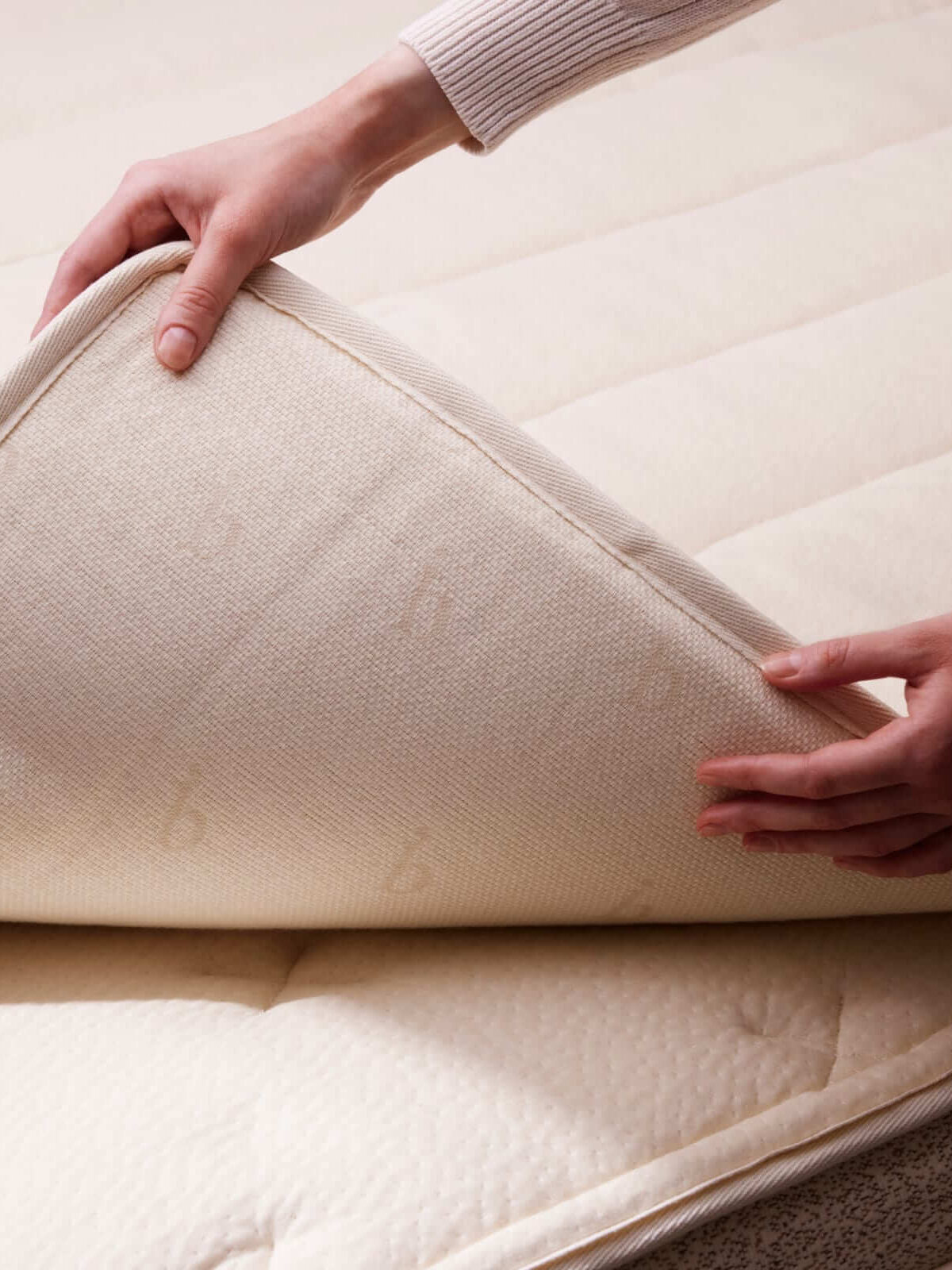 Hands fold back the Birch organic mattress topper.