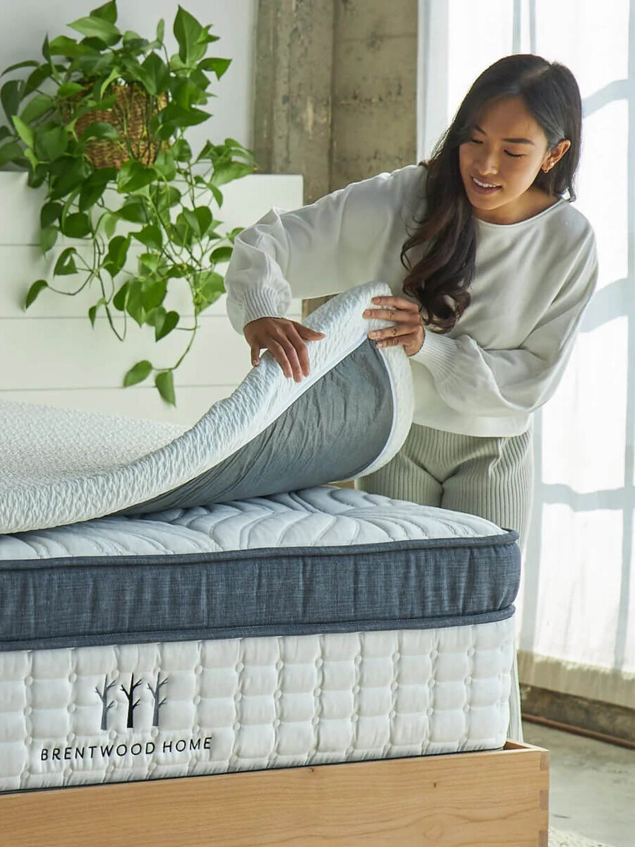 A model peels back the Brentwood Home organic mattress topper.