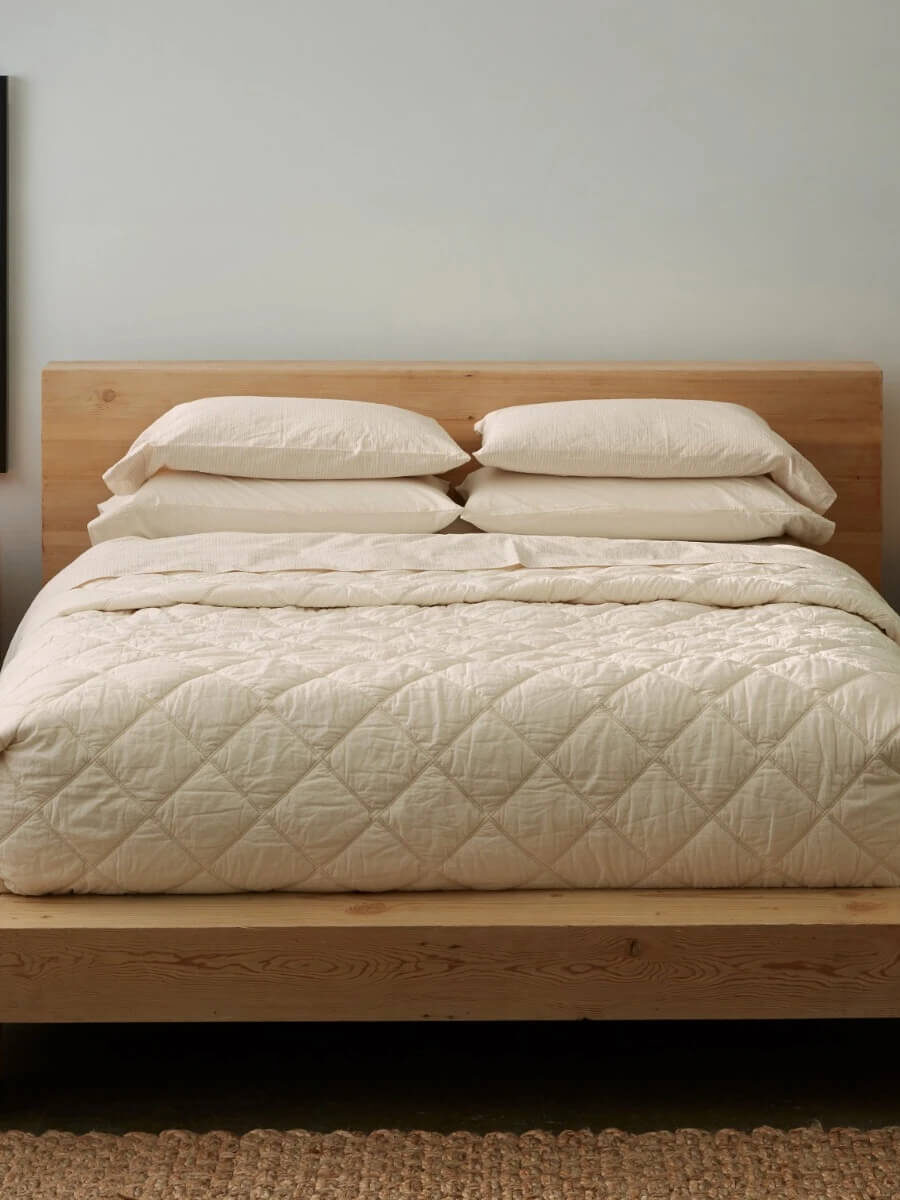 Coyuchi organic comforters in cream on a styled bed.