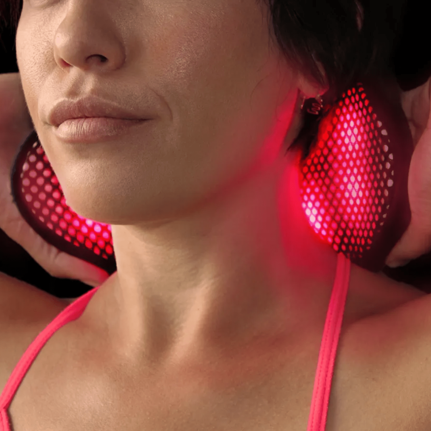 A model wears a red light device around her neck. 