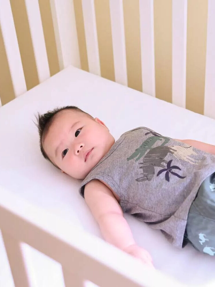 A baby lies on a Lullaby Earth crib mattress