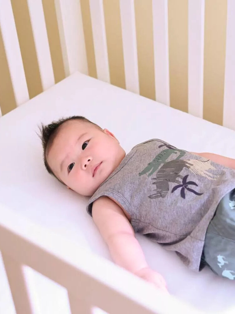 A baby lies on a mattress