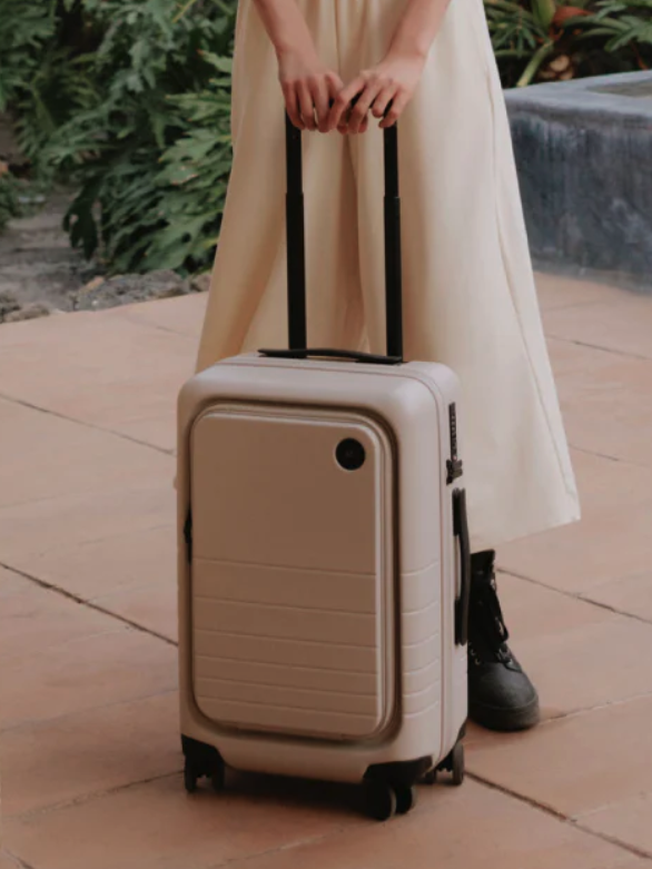 A model rests her hands on the handle of her case. 