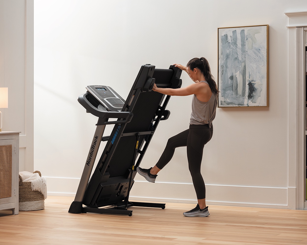 A model folding a NordicTrack treadmill. 