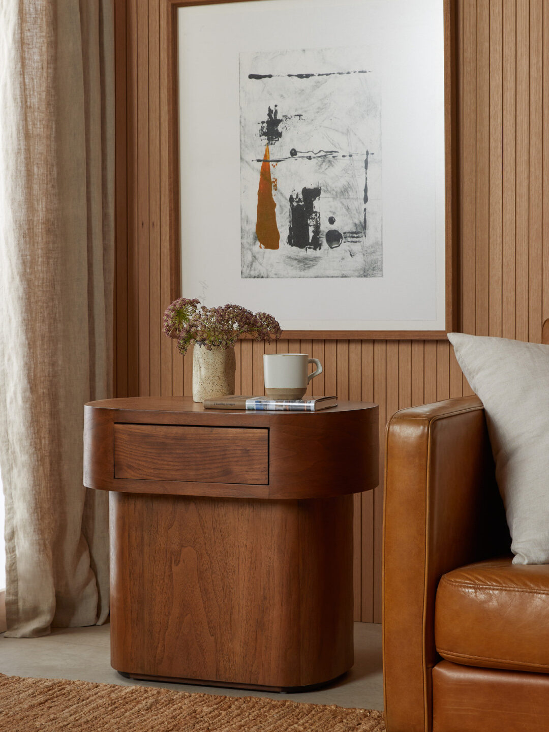 A rounded wooden side table in a styled room.