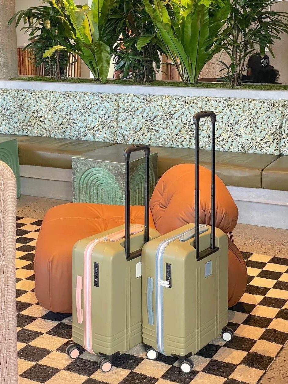 Two cases with their handles extended sit in the lobby of a hotel.