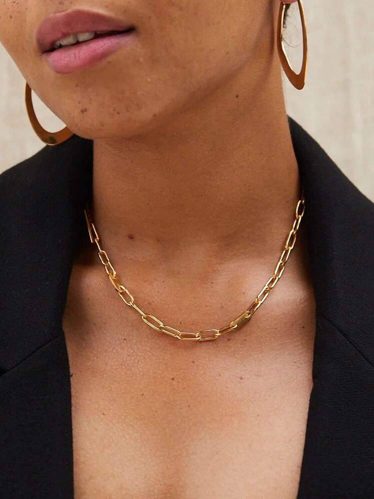 A model wears a chain choker and gold hoop earrings