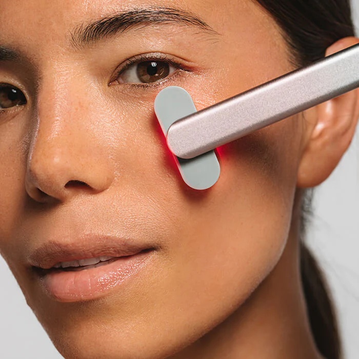 A close up of the Solawave red light wand against a model's cheek.