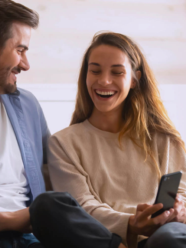 A couple laughing and looking at a phone