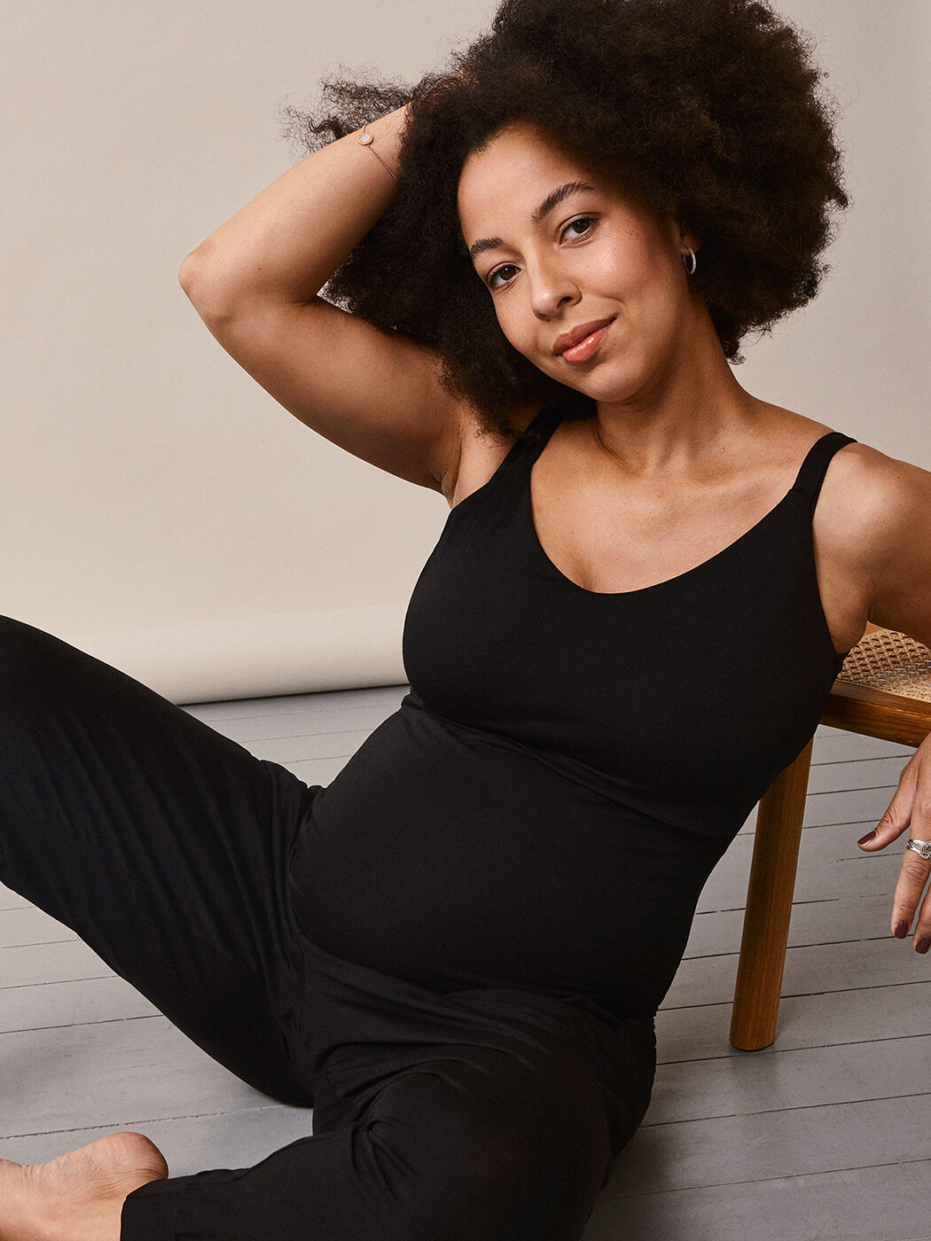 A model in all black has her hand in her hair. 