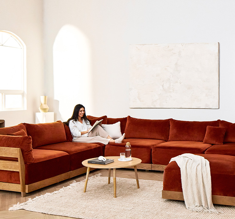 A woman lounges on an Inside Weather couch in a styled living room.