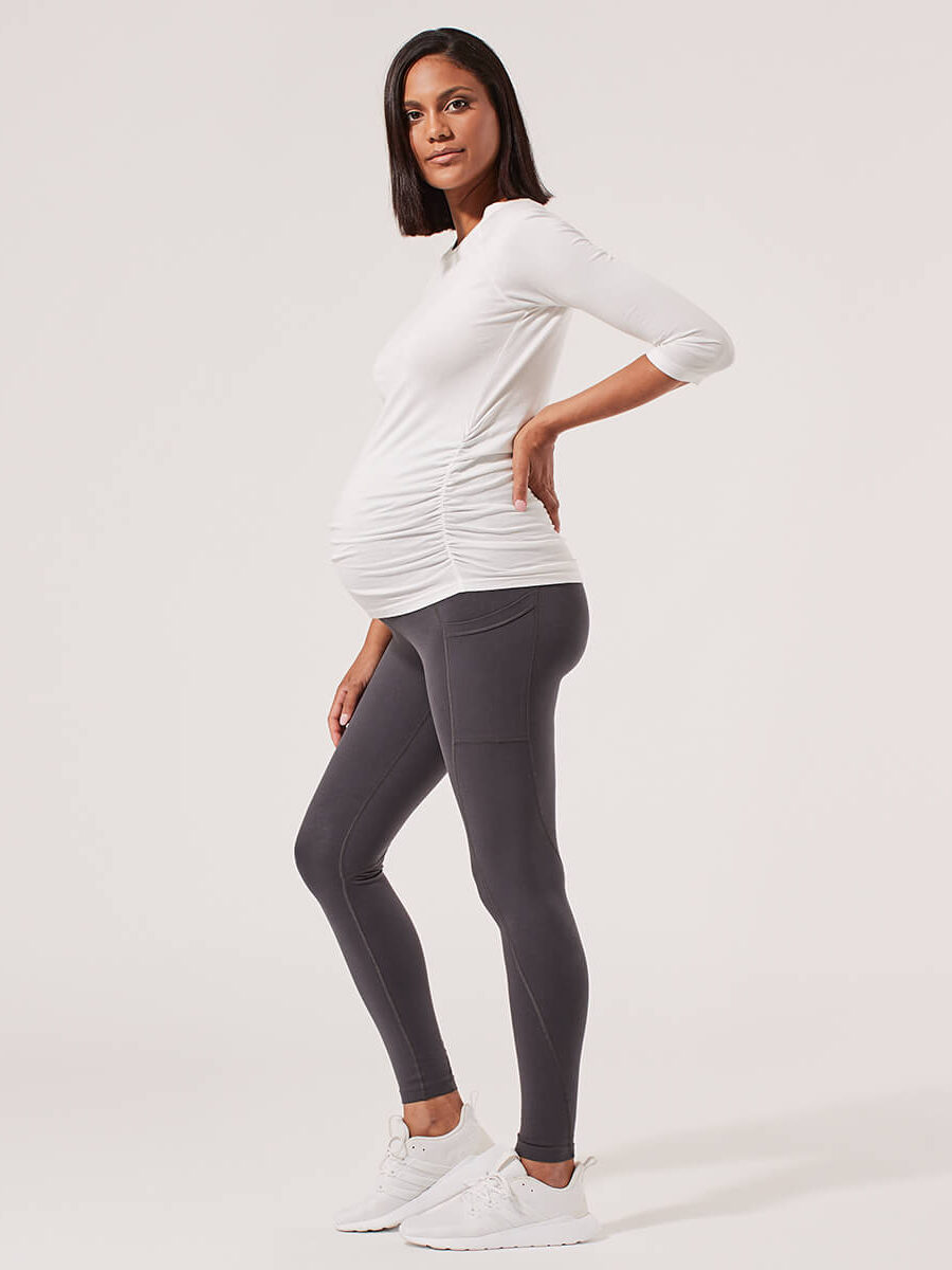 A pregnant model in leggings and a maternity activewear top.