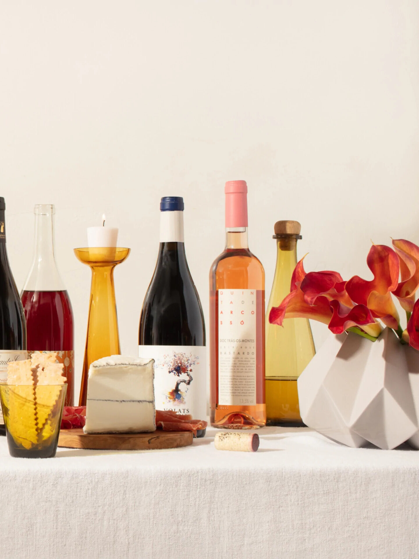 A tablescape of snacks, candles, wine bottles, and more.