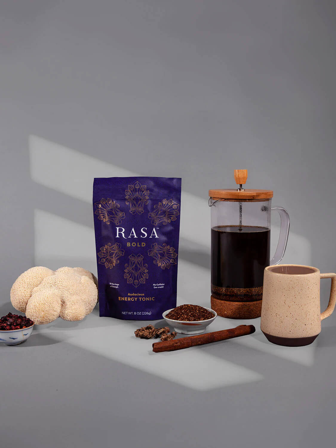 A pack of Rasa coffee alternative with a french press next to it, filled with the brewed blend.