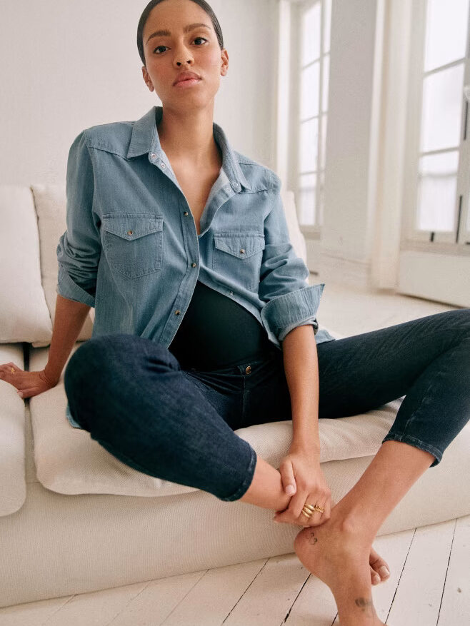 A pregnant woman in jeans and a denim shirt.