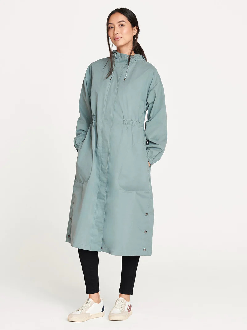 A model wearing a long teal raincoat by thought.