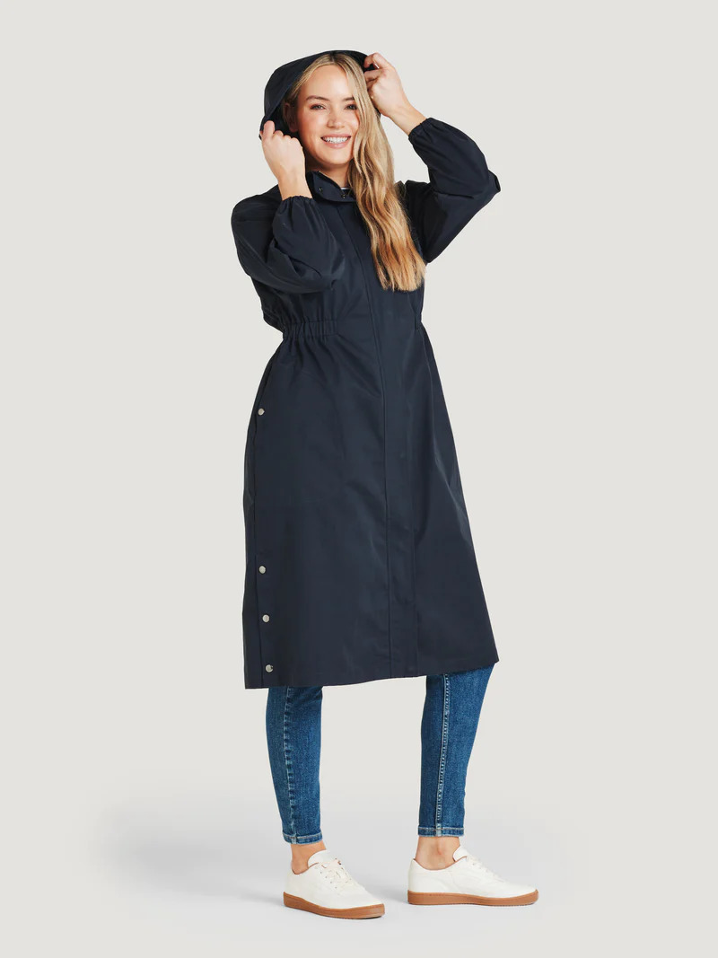 A model wearing a long navy blue raincoat by thought.
