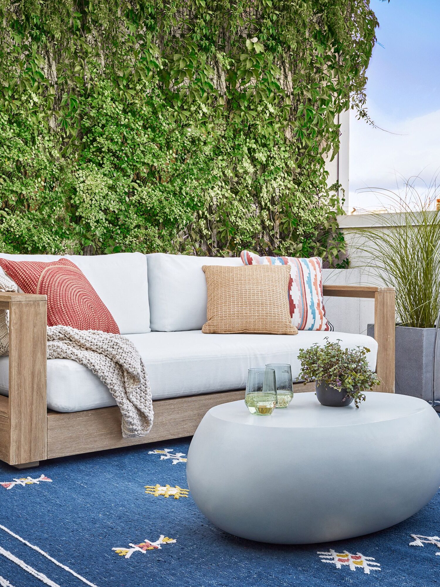 An outdoor sofa with modern round coffee table and outdoor rug
