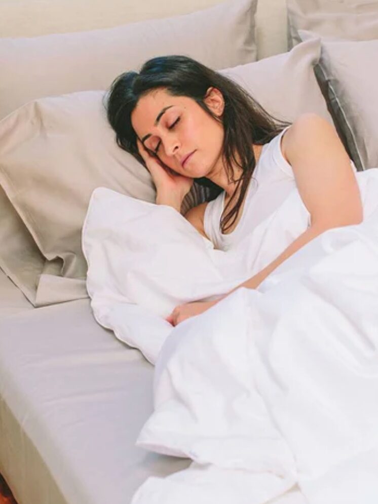 A woman sleeps in a white Nest Bedding organic comforters.