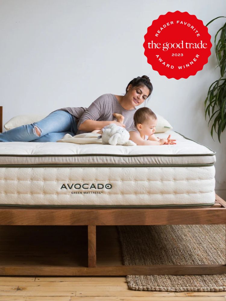 Parent and infant child laying on an Avocado mattress, a red award sticker is overlayed on the top right hand of the image noting that Avocado is one of The Good Trade's reader favorite brands of 2022.