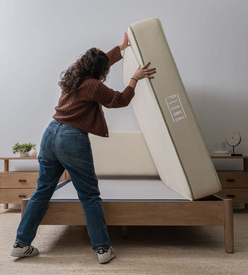 Curly haired person flipping a queen size Plank matress