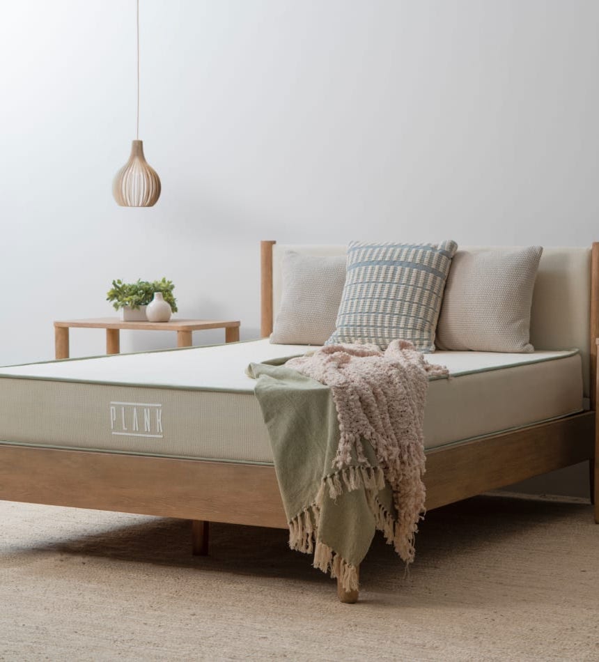 A Plank mattress with pillows and blankets in a styled room.