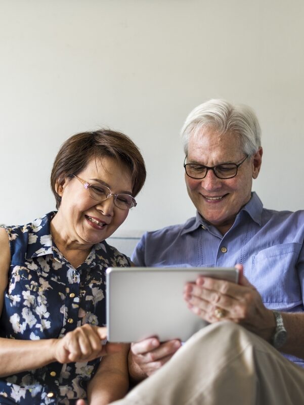 A couple smiles at a tablet together