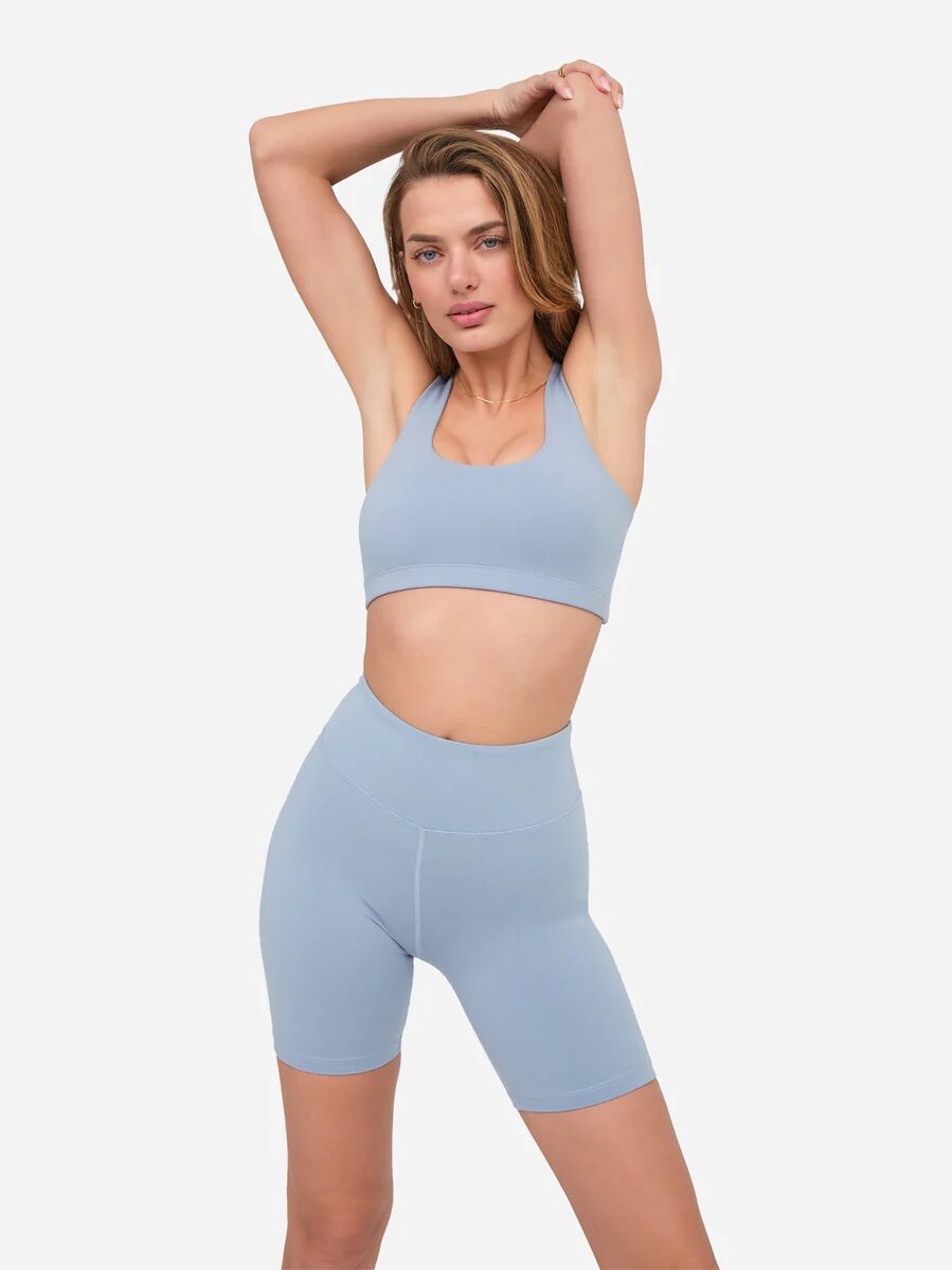 Model in matching light blue sports bra and bike shorts