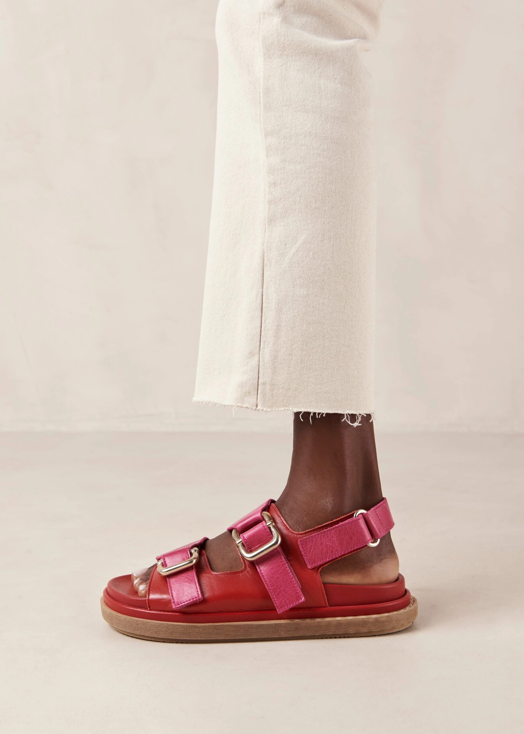 A model's legs in cream cut off jeans wearing red and pink leather Alohas sandals.