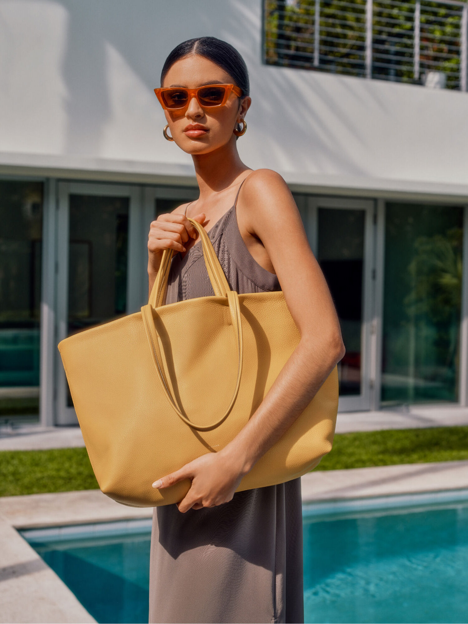 A model holds a yello bag in front of her body.