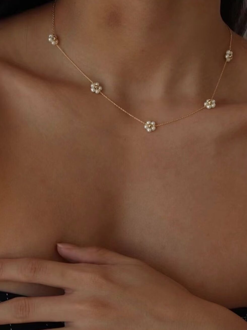 A pearl flower and gold chain choker necklace is displayed on a model.
