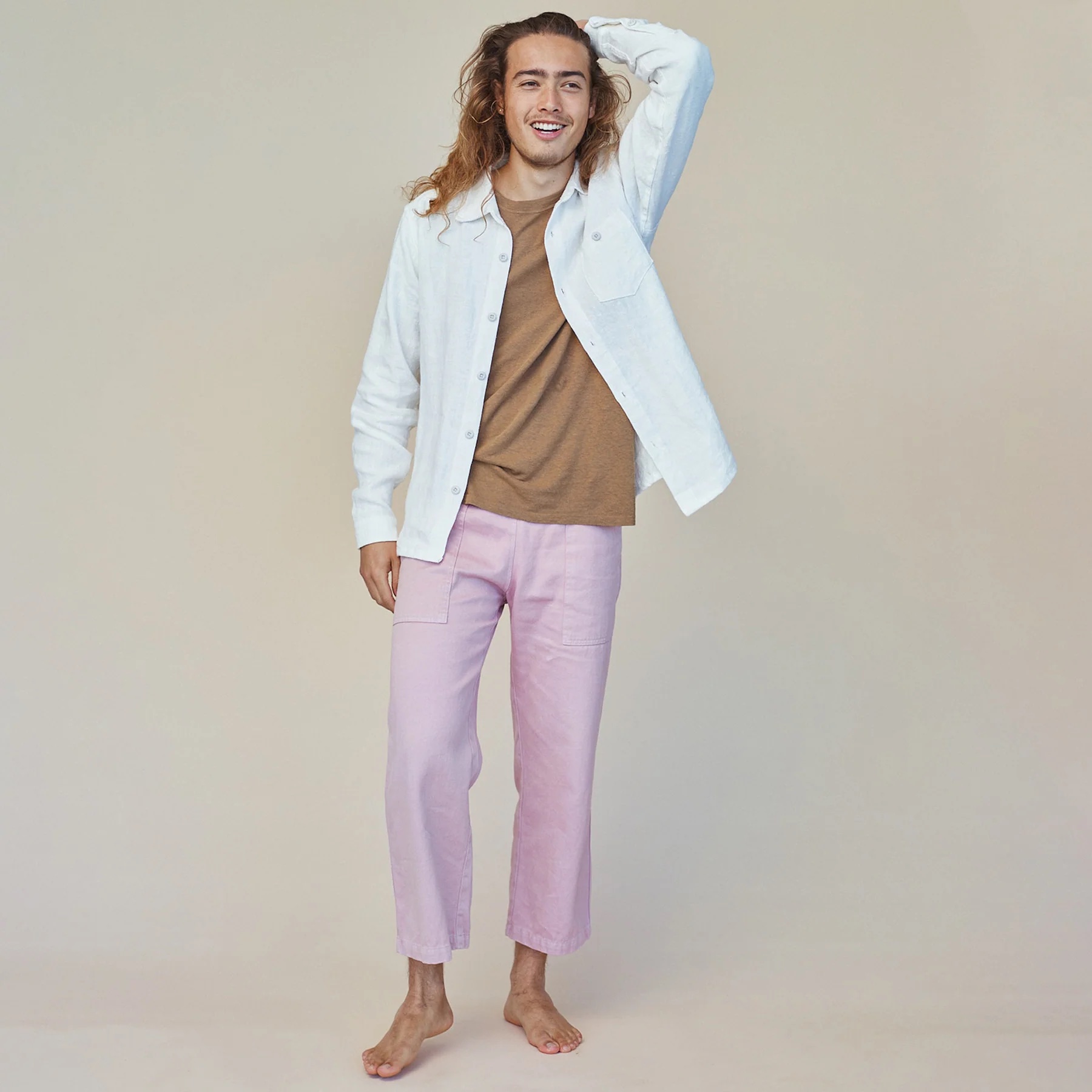 A model wearing Jungmaven lavender hemp pants runs his hand through his hair.