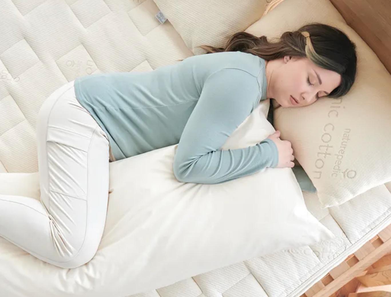 A woman hugs a body pillow.