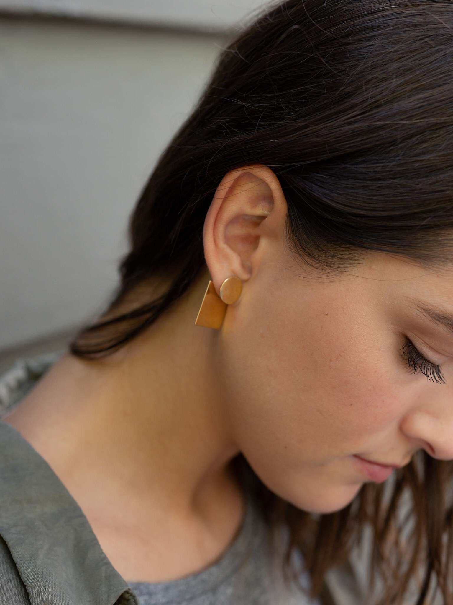 Brass earrings in a model's ear.