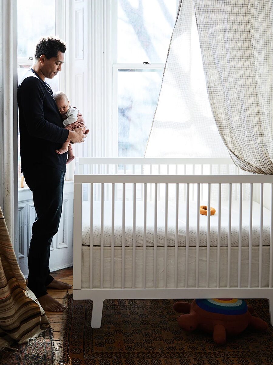White crib with a man and baby standing over it