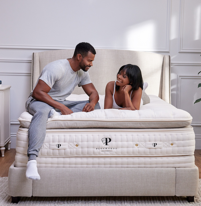 A couple smiles at each other on their Plushbeds natural latex mattress.
