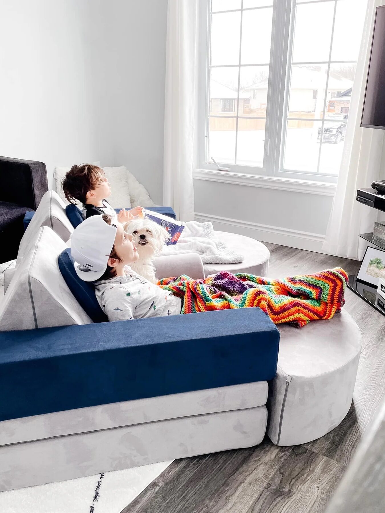 Two boys watch TV from their play couch