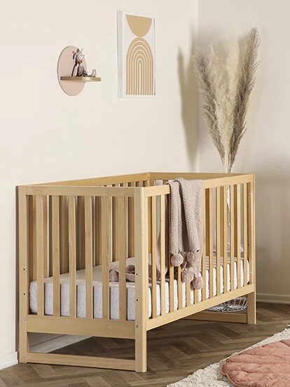 A natural wood crib in a bedroom