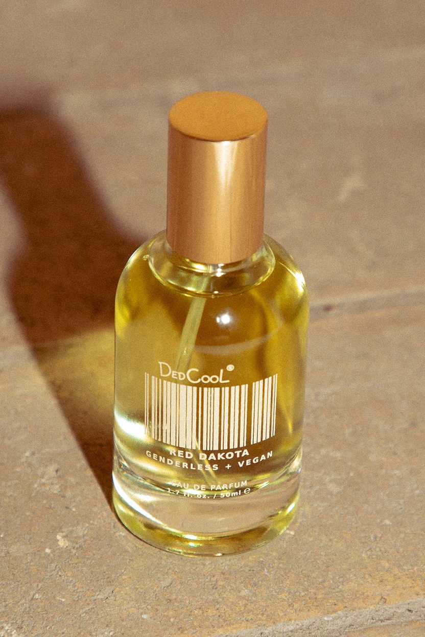 A bottle of fragrance sits on a tile surface.