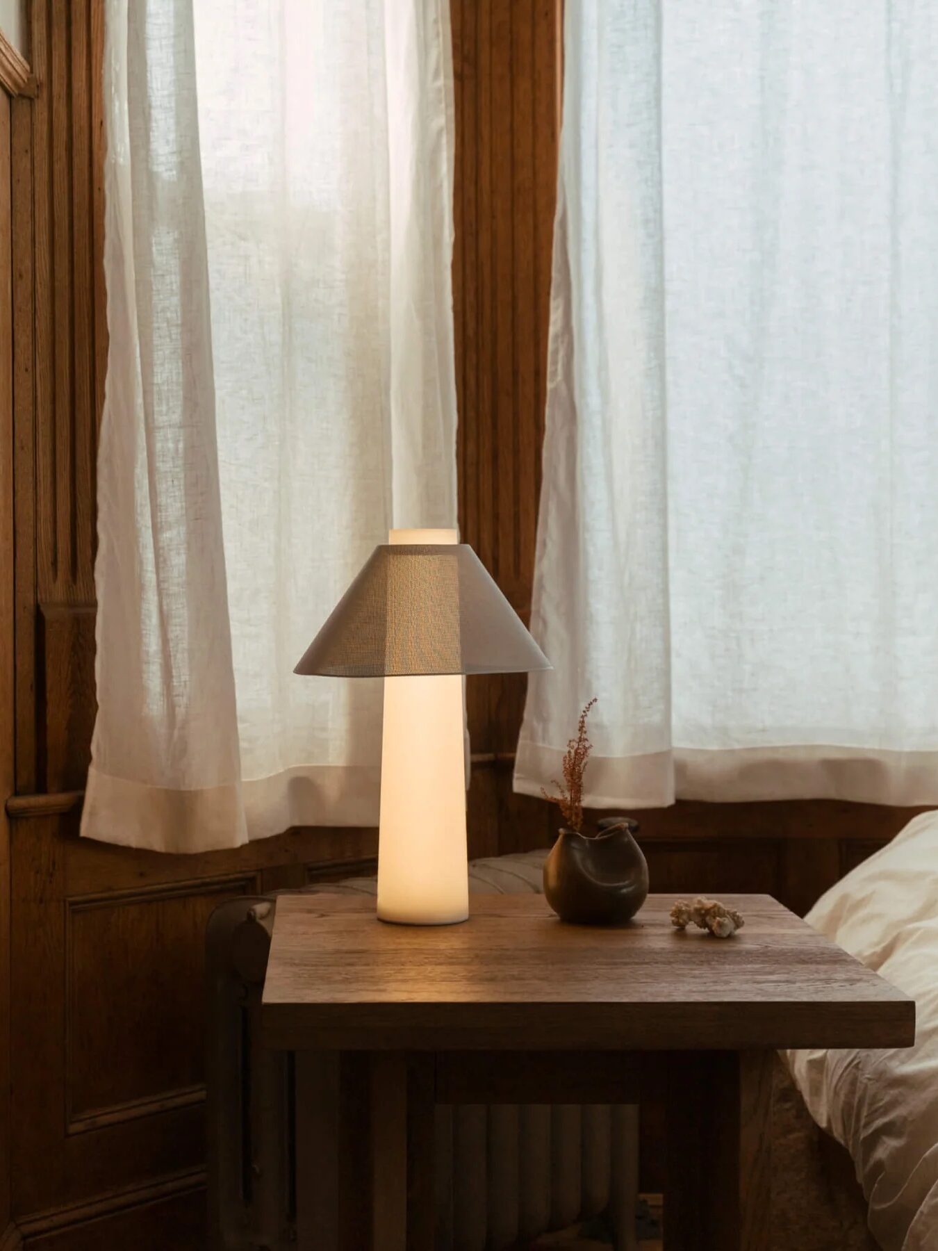 Loftie lamp sits on a bedside table with its base lit.