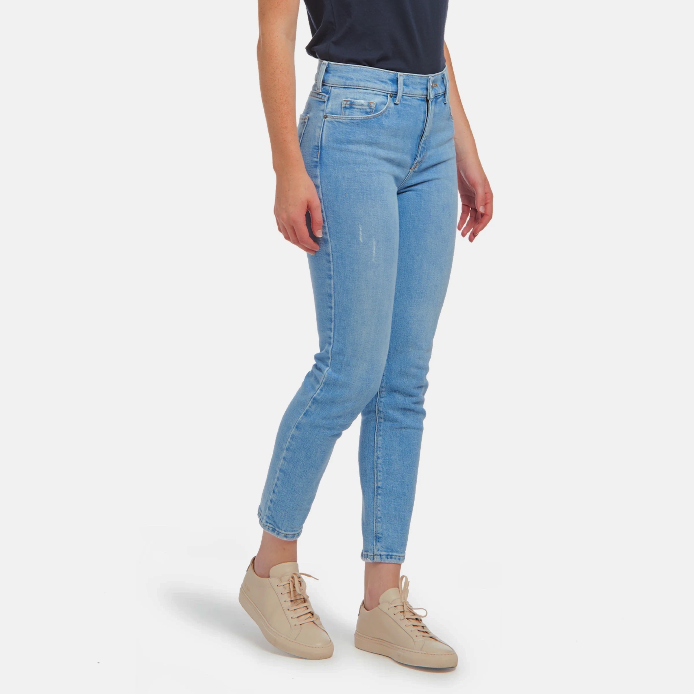 woman from waist down wearing skinny cropped light denim with slight distress on fabric