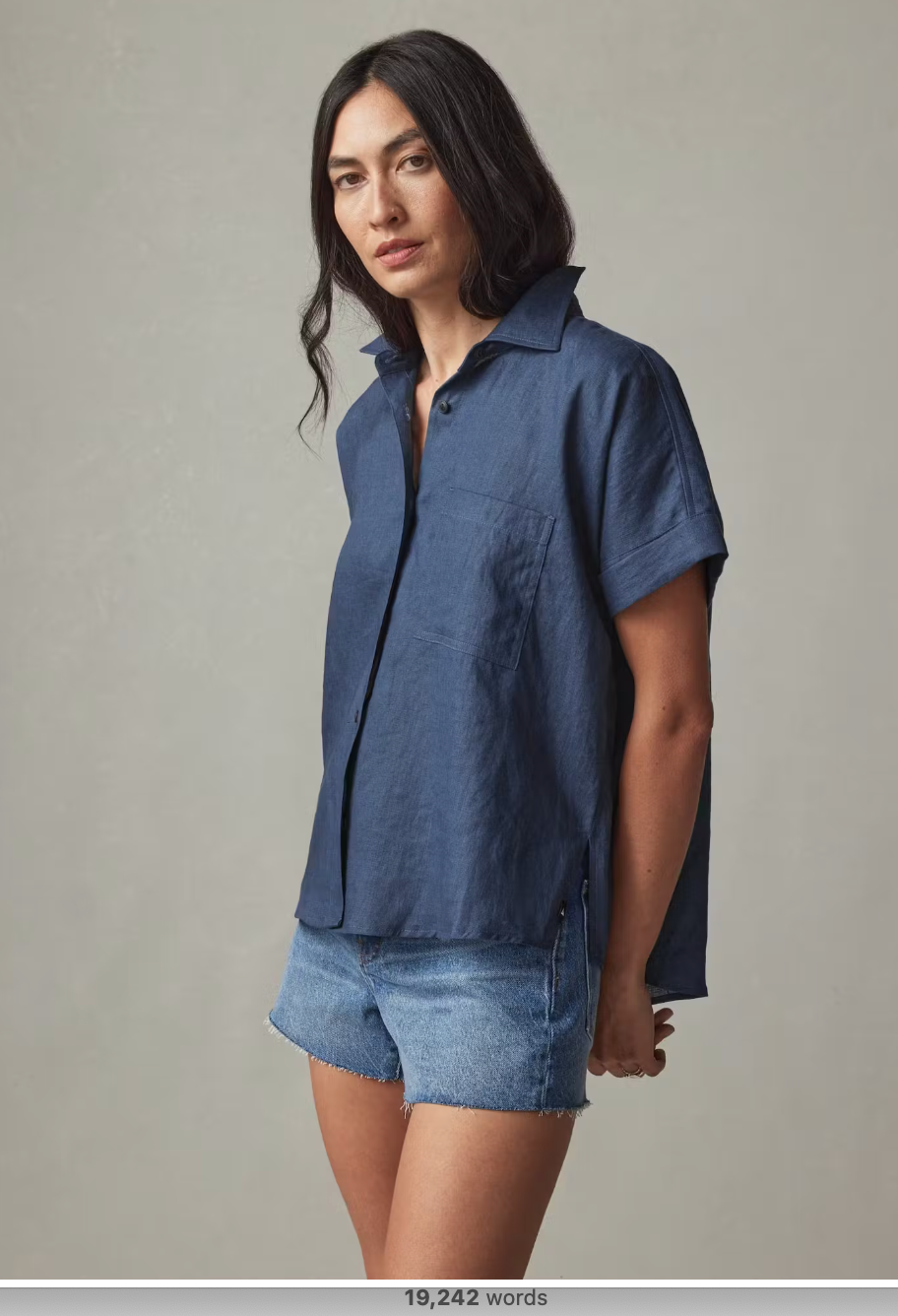 A model in a short sleeved button down and denim shorts.
